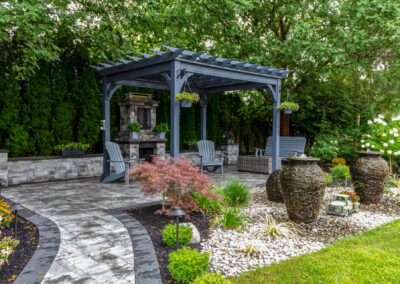 Large gray pergola on pavers with stone fireplace
